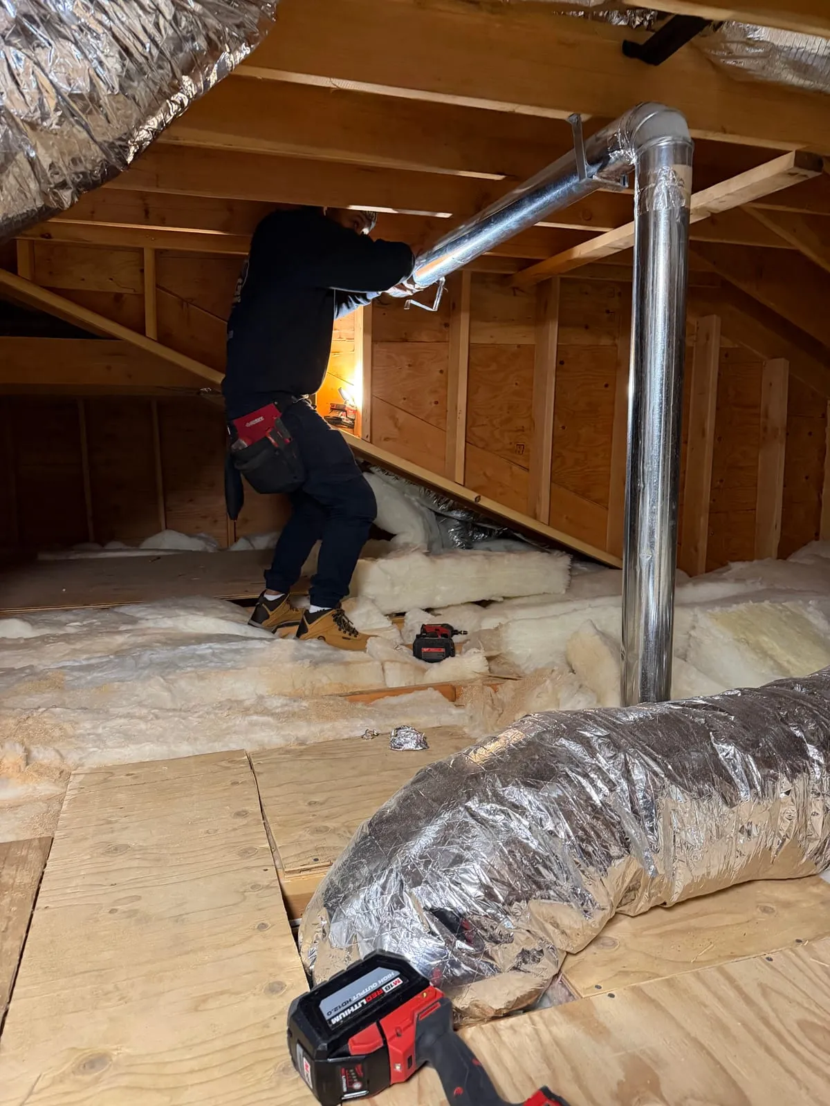 A flexible duct run and metal riser in an insulated attic
